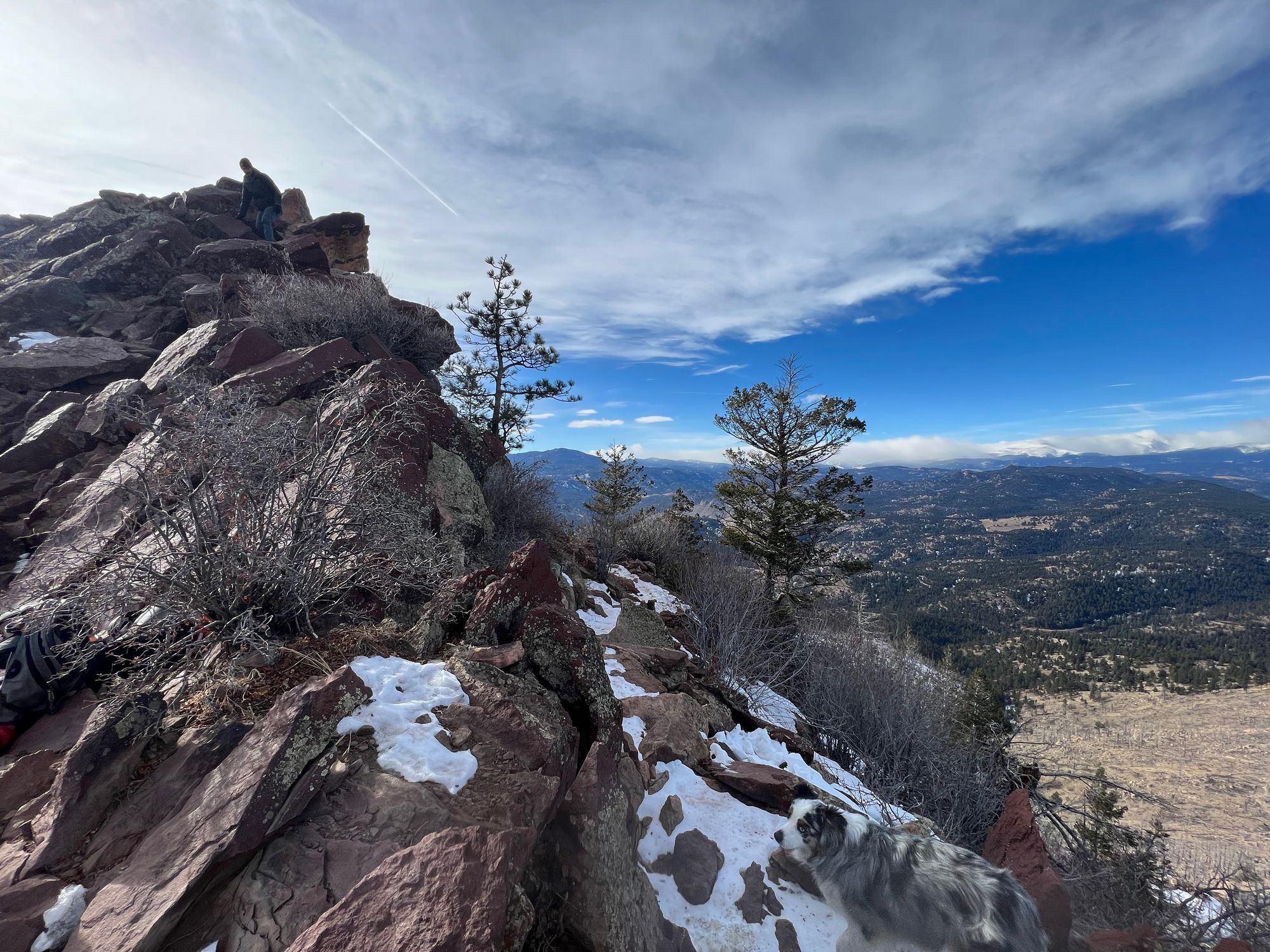 View from the Bear Peak summit with the true summit, and a person, on the left and the Rocky Mountains in the distance to the right